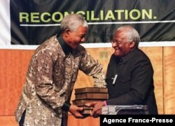 In this file photo taken on Oct. 29, 1998 South African President Nelson Mandela (L) receives a five volumes of Truth and Reconciliation Commission final report from Archbishop Desmond Tutu (R) in Pretoria.