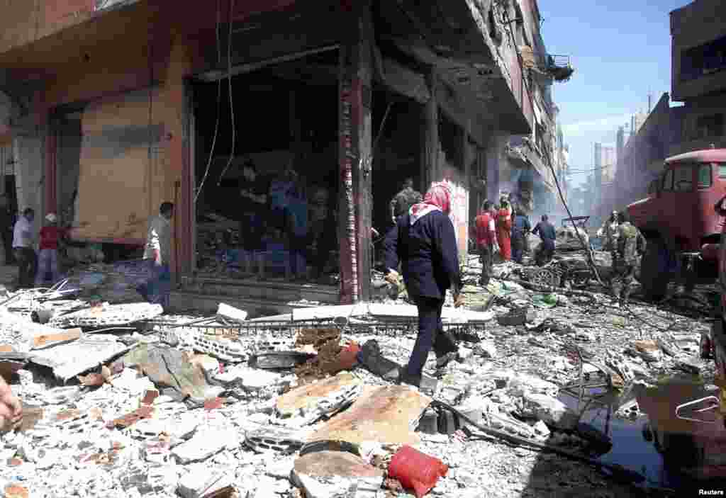 People gather at the site of two car bomb attacks at al-Abassia roundabout in Homs, April 29, 2014. (SANA) 