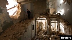 A Free Syrian Army fighter carries his weapon as he walks down the stairs of the damaged former Immigration and Passport building in Aleppo, Oct. 2, 2013.