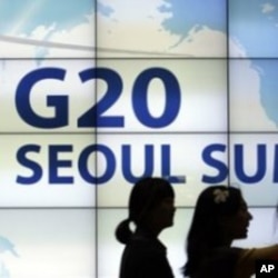 ຜູ້ຍິງສອງຄົນກໍລັງເດີນຜ່ານປ້າຍໂຄສະນາກອງປະຊຸມສຸດຍອດຂອງ ຂອງ​ກຸ່ມ 20 ​ເສດຖະກິດ​ທີ່​ສໍາຄັນ​ຂອງ​ໂລກ ຫລື G20 ທີ່ຢູ່ໃນໜ້າຈໍ ເທິງຝາອາຄານໃຫຍ່ ແຫ່ງນຶ່ງໃນະຄອນຫລວງ ໂຊລ, ເກົາຫລີໃຕ້