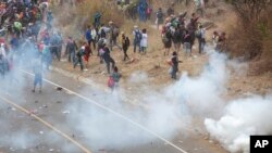 Honduran migrants hurl stones at Guatemalan soldiers amid tear gas in Vado Hondo, Guatemala, Sunday, Jan. 17, 2021.