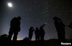 People look at the night sky using night vision goggles during an UFO tour in desert outside Sedona