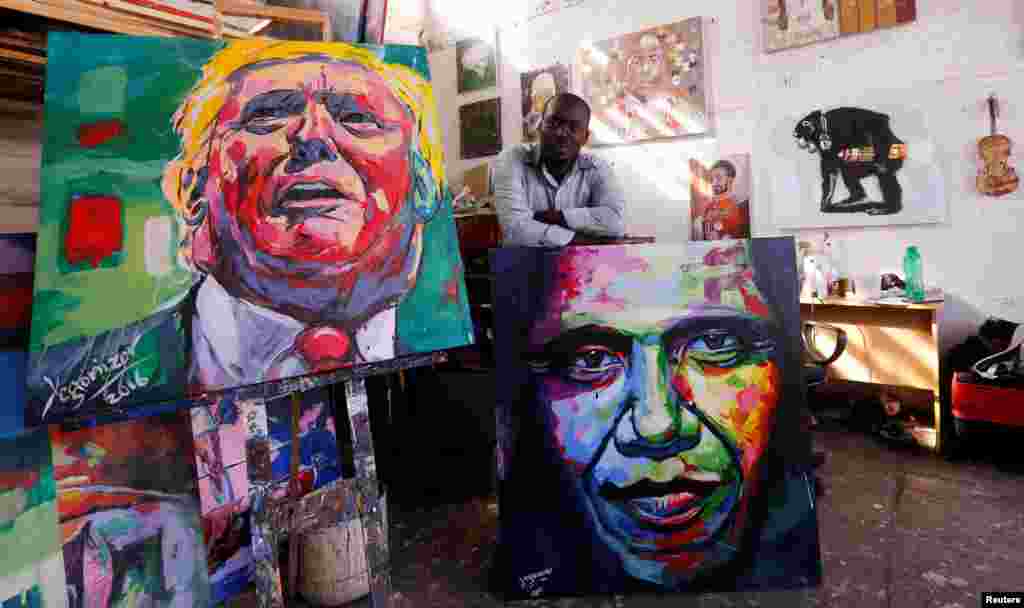 Pelukis Kenya, Evans Yegon berpose dengan lukisannya, Donald Trump (kiri) dan Barack Obama di studionya di Nairobi, Kenya.