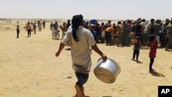 Syrian refugees gather for water at Ruqban border camp in northeast Jordan. Syrian refugees and international aid officials say little water and no food has reached 64,000 Syrian refugees stranded in the desert since Jordan sealed its border in response t