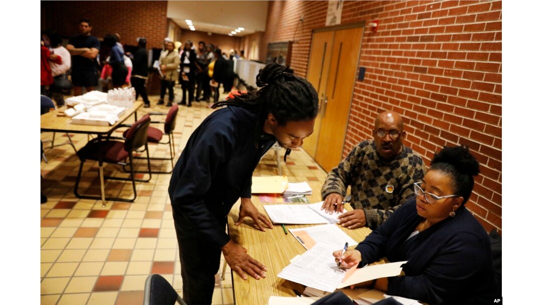 Sebastian Snelling, left, is given instructions on using a paper ballot as the precinct switched over from electronic voting machines after a judge ordered the location to stay open until 10 p.m., in Atlanta, Nov. 6, 2018.