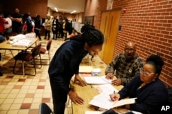 Sebastian Snelling, left, is given instructions on using a paper ballot as the precinct switched over from electronic voting machines after a judge ordered the location to stay open until 10 p.m., in Atlanta, Nov. 6, 2018.