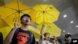 Hong Kong teenage student leader Joshua Wong, left, shouts slogans with supporters outside a magistrates' court in Hong Kong, Wednesday, Sept. 2, 2015. 