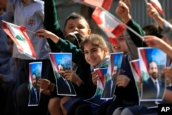 Lebanese students wave portraits of Prime Minister-designate Saad Hariri and Lebanese flags as they celebrate the announcement, in the southern port city of Sidon, Lebanon, Nov. 3, 2016.