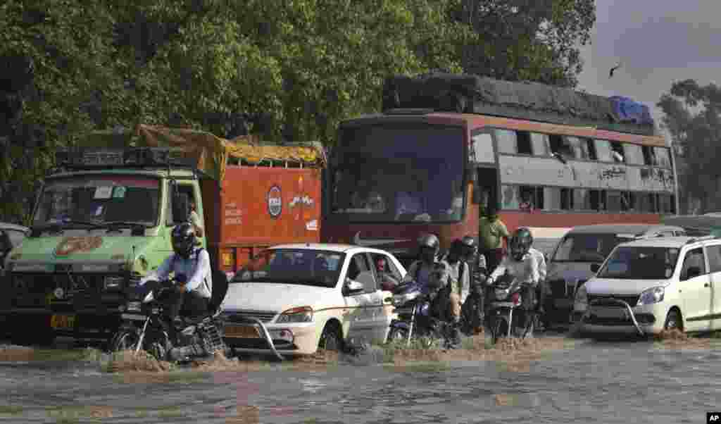 Commuters travel on a flooded road after a rise in the water levels of the Yamuna River in New Delhi, India, June 20, 2013. 