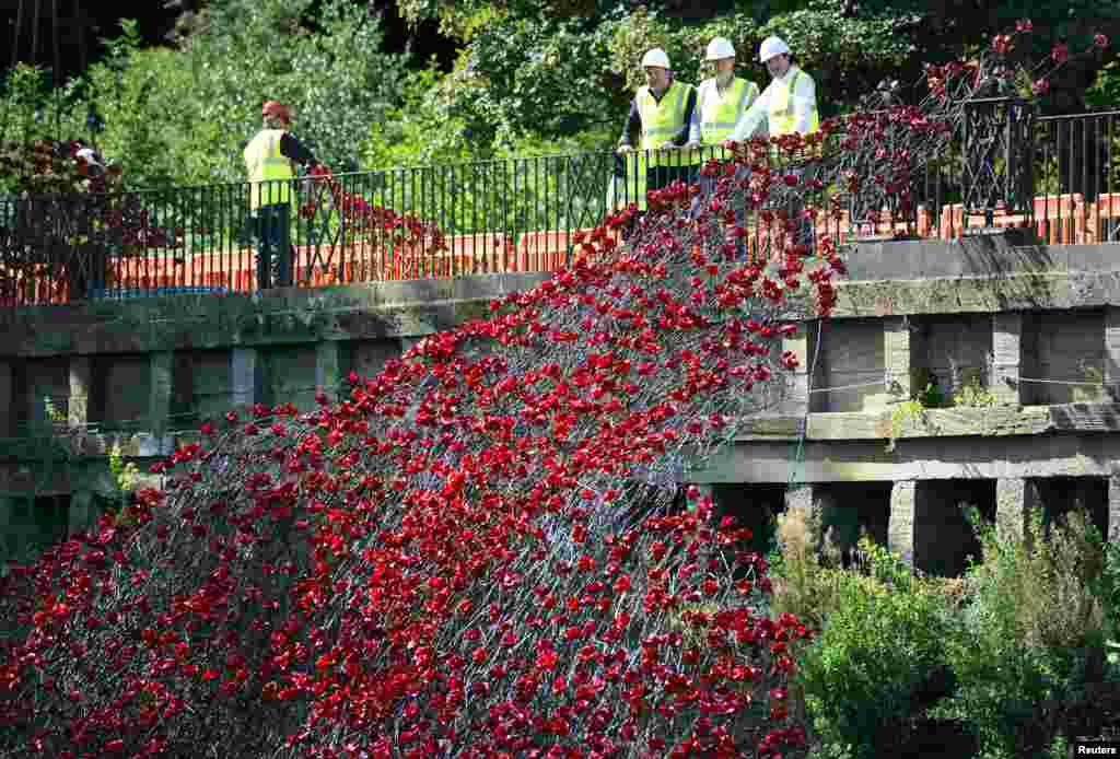 Britain&#39;s Chancellor of the Exchequer George Osborne (R) stands with artist Paul Cummins (3rd R) as they look at the construction of his ceramic poppy sculpture &#39;Wave&#39; at the Yorkshire Sculpture Park in Wakefield, Britain.