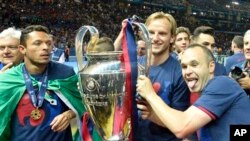Barcelona's Adriano Correia, Ivan Rakitic and Andres Iniesta, from left, celebrate with the trophy after winning 3-1 the Champions League final soccer match between Juventus Turin and FC Barcelona at the Olympic stadium in Berlin Saturday, June 6, 2015. (