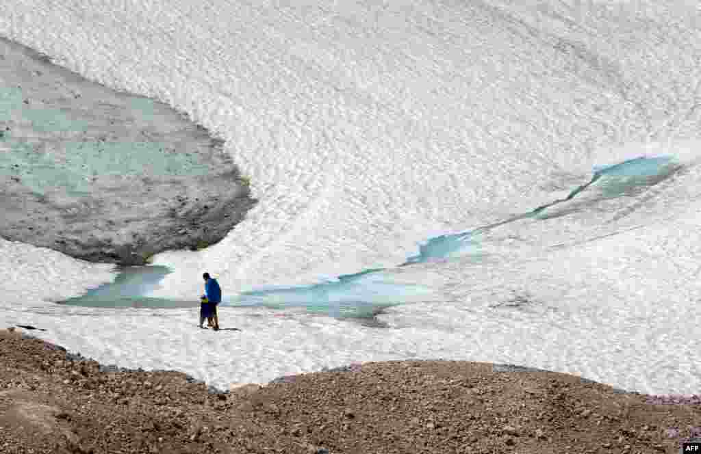Dua pejalan kaki menyusuri gletser Schneeferner di gunung tertinggi Jerman, Zugspitze dekat Garmisch-Partenkirchen, Jerman selatan.