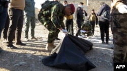 A member of Iraqi security forces put in a plastic bags the remains of people killed by the Islamic State group that were found in a mass grave on Jan. 26, 2016, a day after it was discovered in the Al-Jamiya area of central Ramadi. 