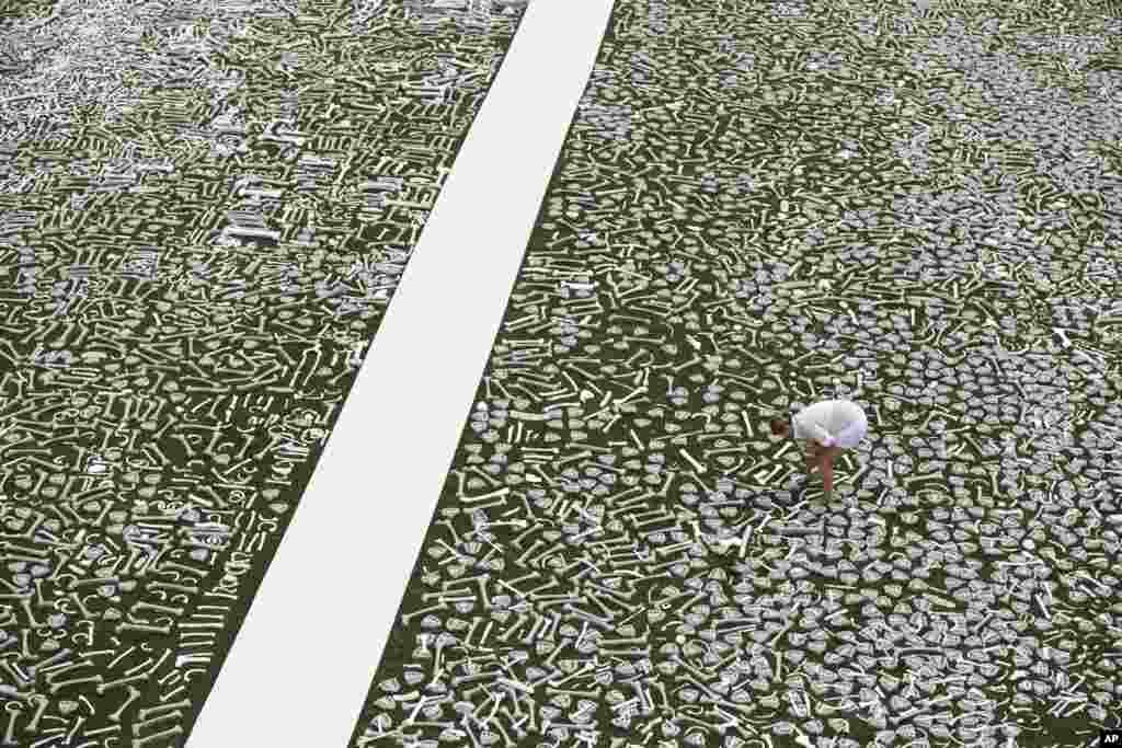 Rochelle Campbell of Washington places human bones, crafted by students, artists and activists, in place on the lawn of the National Mall in Washington, June 8, 2013, during a massive installation called One Million Bones, symbolic of a mass grave and a visible petition for bold action towards an end to genocide and mass atrocities.