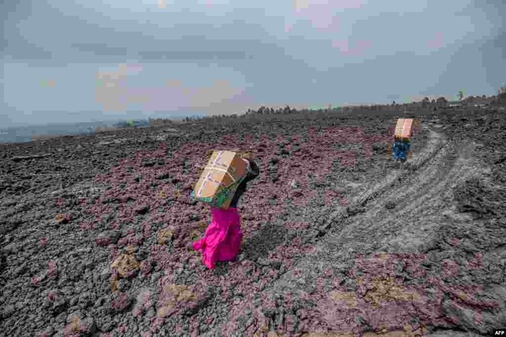 Residents carry goods on their backs while they cross a lava covered field in Buhene, north of Goma, Democratic Republic of Congo.