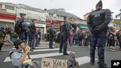 French gendarmes stand near an anti G20 demonstrator who takes part in protest against globalization and tax havens, at the French-Monaco border in Cap d'Ail, southeastern France, November 3, 2011.