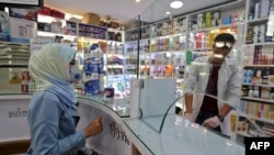 People wearing protective masks shop at a pharmacy in the Iranian capital Tehran, Feb. 24, 2020. 