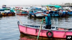 El pescador Máximo Castro apunta hacia el sur, la dirección de donde provino el derrame de petróleo, en su bote en la contaminada bahía de Ancón en Lima, Perú, el viernes 21 de enero de 2022.