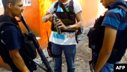 Miembros armados de los llamados grupos de autodefensa miran las armas incautadas a miembros de cárteles cuando les quitan el control de la comunidad La Huerta, en el estado de Michoacán, México. [Foto de archivo]