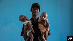 আবরাহা কিনফে গেব্রেমারিয়াম (৪০) নামের এই টিগ্রায়ান একটি উদ্বাস্তু শিবিরে তার ৪ মাস বয়সী যমজ কন্যাদের কোলে নিয়ে দাঁড়িয়ে আছেন। 