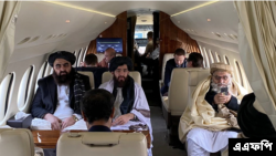 Menteri Luar Negeri Afghanistan Amir Khan Muttaqi (kiri) dan juru bicara kementerian Abdul Qahar Balkhi (tengah) bersama para delegasi Taliban lainnya terlihat dalam pesawat menuju Oslo, Norwegia, di Bandara Kabul pada 22 Januari 2022. (Foto: AFP)