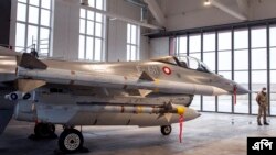 A military police officer stands in front of a Danish Royal Air Force F-16 fighter jet during the welcome ceremony for the reinforcement of the NATO Air Policing Mission at the Siauliai military air force base some 230 km (144 miles) east of the capital Vilnius, Lithuania, Friday, Jan. 28, 2022.