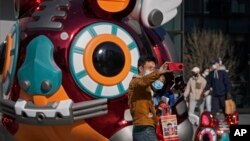 Una pareja con mascarilla para evitar contagios del coronavirus se hace una foto con un tigre robótico colocado como decoración en un centro comercial de Beijing, la víspera del Año Nuevo Lunar, el lunes 31 de enero de 2022.