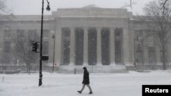 Seorang pejalan kaki melewati salju di luar MIT School of Architecture and Planning selama badai Nor'easter yang kuat di Cambridge, Massachusetts, AS, 29 Januari 2022. (Foto: REUTERS/Nicholas Pfosi)