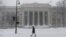 Seorang pejalan kaki melewati salju di luar MIT School of Architecture and Planning selama badai Nor'easter yang kuat di Cambridge, Massachusetts, AS, 29 Januari 2022. (Foto: REUTERS/Nicholas Pfosi)