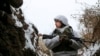 一名军人站在乌克兰东部由亲俄武装分子控制的领土上的战壕中，那里离乌克兰政府军的前线不远。(2022 年 1 月 25 日)