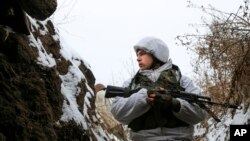 一名军人站在乌克兰东部由亲俄武装分子控制的领土上的战壕中，那里离乌克兰政府军的前线不远。(2022 年 1 月 25 日)
