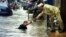 A Cambodian amputee beggar is given money by a passerby while wading in the street flood in Phnom Penh, file photo. 