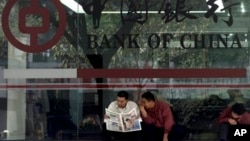 In this undated file photo, men share newspaper outside a branch of the state-run Bank of China, which recently halted business with the Foreign Trade Bank of North Korea.