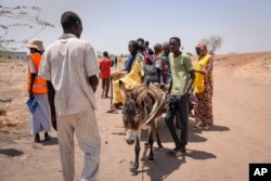 Watu wakivuka mpaka kutoka Sudan kwenda Sudan Kusini kwa mkokoteni unaovutwa na punda wakipokelewa na maafisa wanaofuatilia wakimbizi katika mpaka wa Joda, Sudan Kusini. (AP Photo/Sam Mednick)