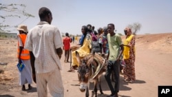 Les gens traversent la frontière du Soudan au Soudan du Sud sur une charrette à âne et s'enregistrent auprès du personnel de surveillance des frontières, au poste frontière de Joda au Soudan du Sud le mardi 16 mai 2023.