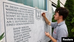 A stone cutter renovates a memorial stone for the 11 Israeli athletes killed by Palestinian militants during the 1972 Olympic Games, at the site of the hostage-taking at the former Olympic Village in Munich, Germany, Aug. 18, 2022.