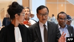 Lawyer Jessica Finelle (L) walks with her client Cambodian opponent in exile and leader of the Cambodia National Rescue Party (CNRP) Sam Rainsy (L), as they arrive at the court house accused in a defamation lawsuit filed by Cambodia's prime minister, in 