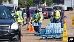 Workers at the Highway 18 Walmart distribute the last of 6,000 cases of water to long line of residents in Jackson, Mississippi, Sept. 1, 2022.