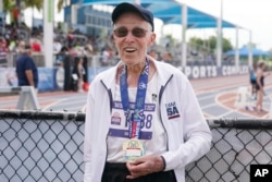 FILE - Richard Soller holds his medal in the 200m final of the National Senior Games in Miramar, Florida, Monday, May 16, 2022. (AP Photo/Marta Lavandier)