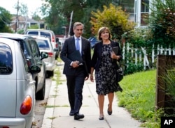 Dan Sideris and his wife, Carrie Sideris, of Newton, Mass., walk along a sidewalk as they return to door-to-door visits as Jehovah's Witnesses, Sept. 1, 2022, in Boston. From coast to coast, members of the Christian denomination fanned out in cities and towns Thursday to share literature and converse about God for the first time since March 2020.