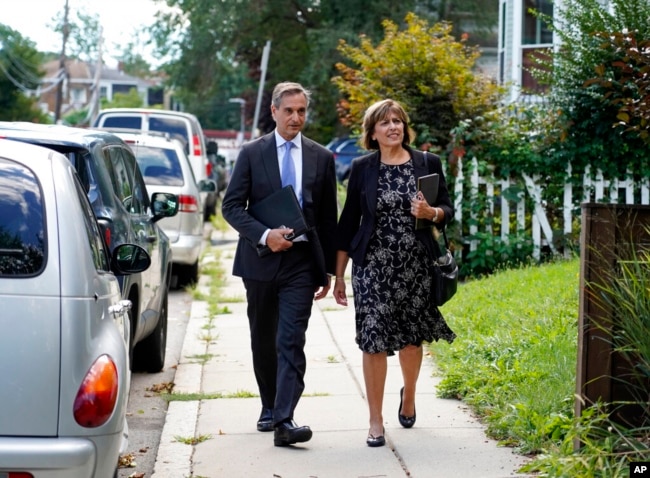 Dan Sideris and his wife, Carrie Sideris, of Newton, Mass., walk along a sidewalk as they return to door-to-door visits as Jehovah's Witnesses, Sept. 1, 2022, in Boston. From coast to coast, members of the Christian denomination fanned out in cities and towns Thursday to share literature and converse about God for the first time since March 2020.