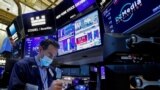 A trader works, as Federal Reserve Chair Jerome Powell is seen delivering remarks on screens