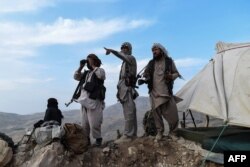 In this picture taken on July 15, 2021, Afghan militia fighters keep a watch at an outpost against Taliban insurgents at Charkint district in Balkh Province.