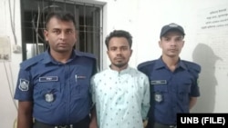 পুলিশের সাথে আটক ঝুমন দাশ। (ফাইল ছবি) 