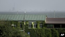 FILE - A man walks on a pedestrian crossing point near the Dnipro river and Zaporizhzhya nuclear plant on the other side in Nikopol, Ukraine, Aug, 22, 2022.