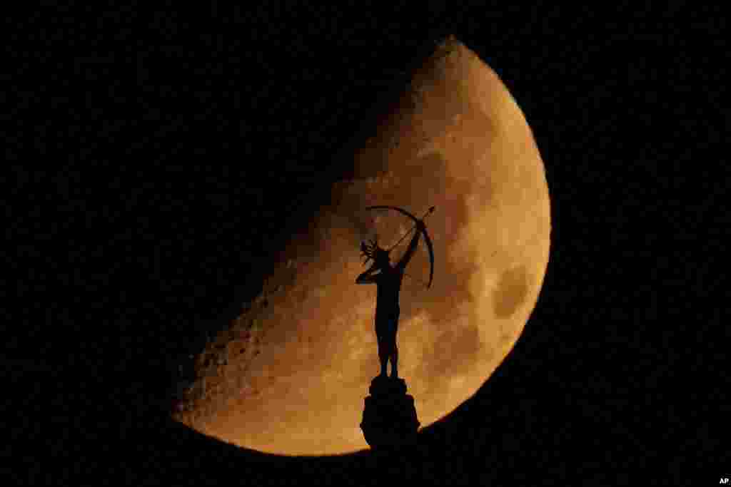 A statue of a Kansa warrior titled &quot;Ad Astra,&quot; atop the Kansas Statehouse is silhouetted against the setting moon in Topeka, Kansas.