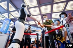 北京举行的2022世界机器人大会上一个机器人与参观者握手。（2022年8月18日）
