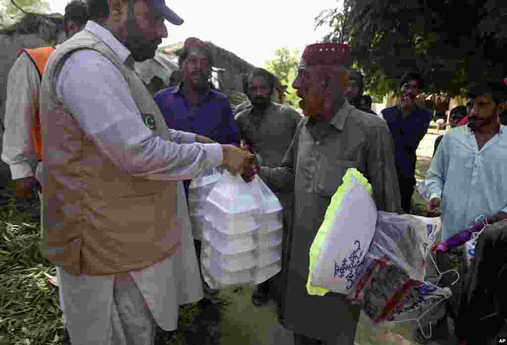 Victims of the unprecedented flooding from monsoon rains receive relief aid, organized by the Islamic group Jamaat-e-Islami Pakistan, in Sukkur, Pakistan, Sept. 4, 2022. 