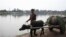 A man transporting green fodder on a buffalo cart walks down a road along stranded flood water, following rains and floods during the monsoon season in Nowshera, Sept. 4, 2022. 