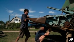 Oleksandr Pasko, right, works to repair a harvester machine in preparation to the sunflowers harvesting in the village of Zorya, Ukraine, Sept. 2, 2022.